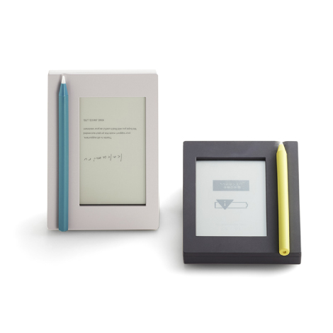 キングジムの電子メモ「カクミル」。ノートの“のど”をモチーフにしたペンの置き場所（くぼみ）がある白い筐体。横置きで書きやすく、縦置きで見やすい画面構成。文房具のような佇まいと、余白を意識したグラフィックデザインが特徴的な製品外観。