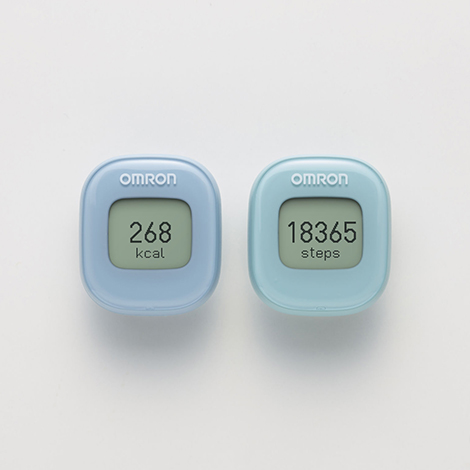 オムロン ヘルスケア株式会社 歩数計 HJ-327Tのプロダクトデザイン。角が丸い正方形のプラスチック筐体。淡いブルーとミントグリーンの2つの個体が並び、中央の液晶画面に歩数と消費カロリーが黒いデジタル数字で表示されている。