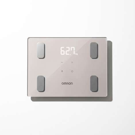 ムロンヘルスケア株式会社 体重体組成計 カラダスキャン KRD-403Tのプロダクトデザイン。表面は光沢のあるガラス製で、四隅にグレーの長方形電極が配置されている。中央上部に白いLEDのデジタル数字が表示され、中央下部にブランドロゴが印字されている。