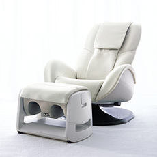 オムロンヘルスケア株式会社 Pisuのフットマッサージャー。白を基調としたレザー素材の丸みを帯びたマッサージチェアと、足を入れるための凹みが設けられたオットマン型のフットマッサージャーユニット。椅子の土台は黒い円盤状のパーツで構成されている。