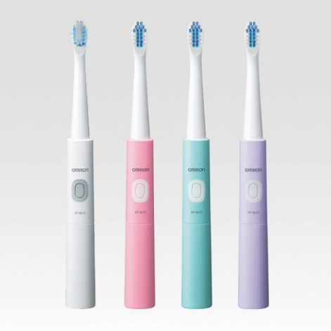 オムロンヘルスケア株式会社 音波式電動歯ブラシ「HT-B210シリーズ」のプロダクトデザイン。ホワイト、ピンク、ミントグリーン、パープルの4色のスリムな円柱状本体。中央に楕円形の操作ボタンとOMRONのロゴが配置され、上部に白い替えブラシが装着された製品が並ぶ構図。