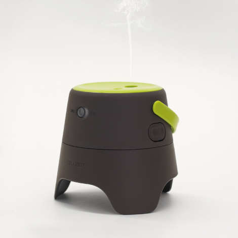 住友化学株式会社 ストロンテック 屋外用虫よけのプロダクト。ダークブラウンの円錐台形ボディに、ライムグリーンの天面とハンドルが配されたデザイン。3本の脚で接地し、天面中央の穴からミスト状の薬剤が垂直に放出される。