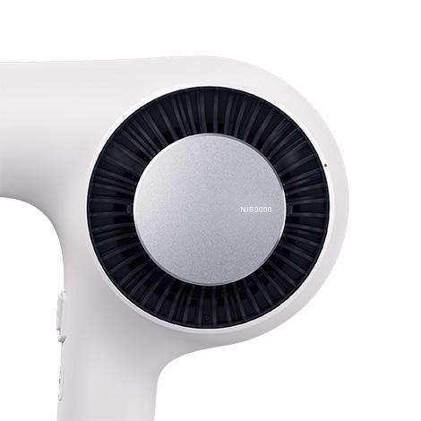 テスコム Nobby by TESCOM NIB3000 ヘアードライヤーの製品外観。マットオフホワイトの筐体側面に、黒い同心円状の吸込口とシルバーのアクセントを配置した、洗練されたデザイン。